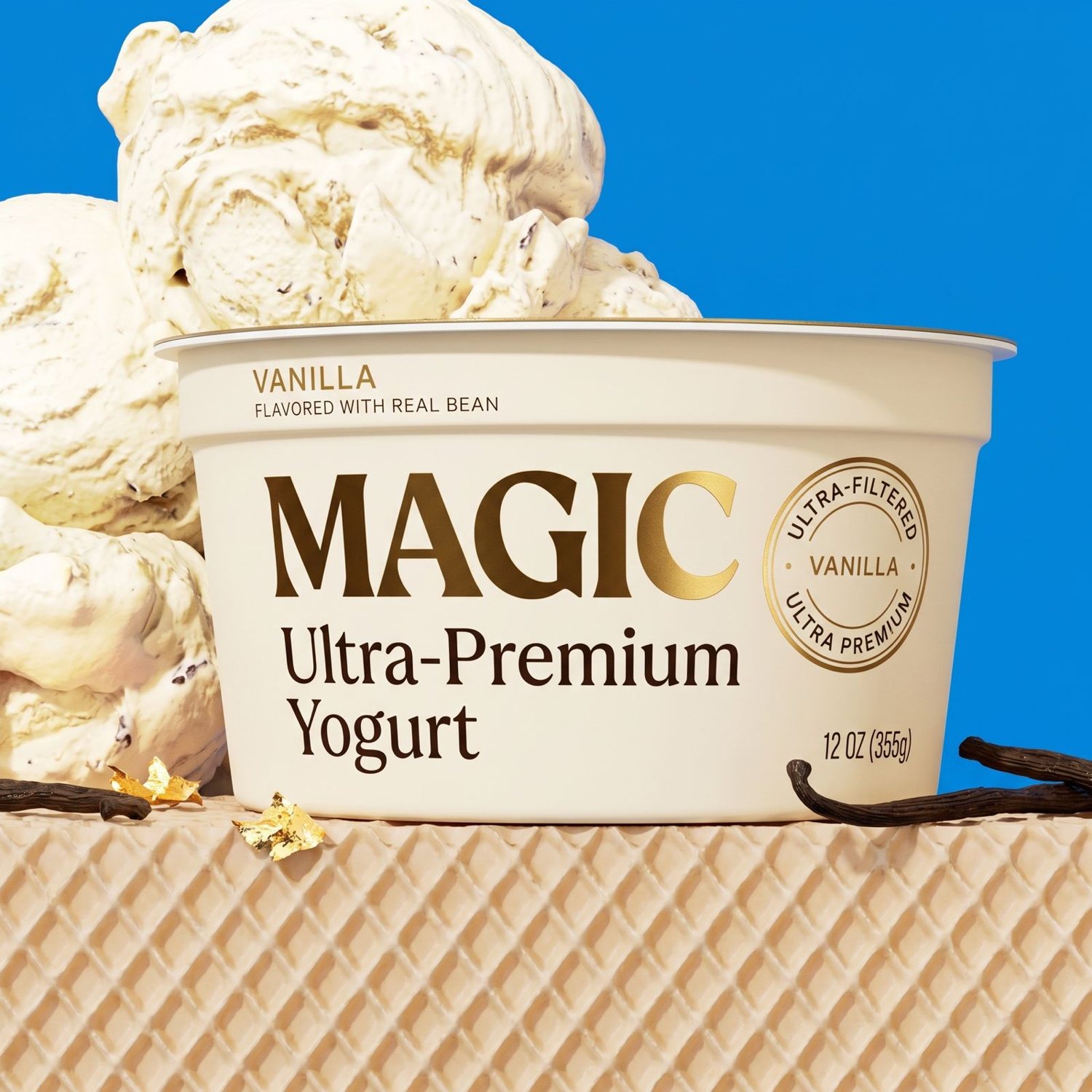 MAGIC ultra-premium vanilla yogurt tub surrounded by vanilla-fleck scoops on a royal blue set